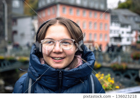 Smiling teenager girl with braces, eyeglasses and headphones Smiling teenager girl with braces, eyeglasses and headphones 136023218