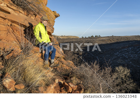 senior male hiker with trekking poles at sandstone cliff in Lory State Park in COlorado foothills 136023348