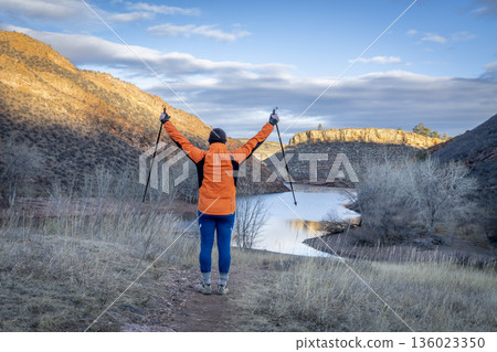 senior male hiker with trekking poles in Lory State Park in Colorado foothills with Horsetooth Reservoit in background 136023350
