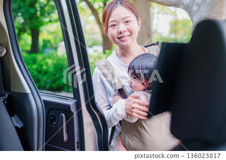 A woman riding in a taxi with her child in a baby carrier A woman riding in a taxi with her child in a baby carrier 136023817