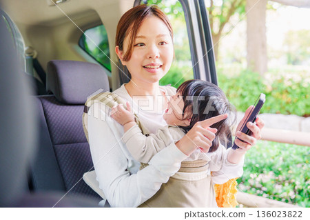 A woman riding in a taxi with her child in a baby carrier A woman riding in a taxi with her child in a baby carrier 136023822