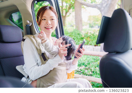 A woman riding in a taxi with her child in a baby carrier A woman riding in a taxi with her child in a baby carrier 136023823