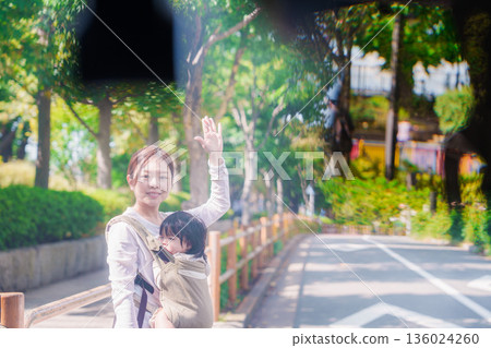 A woman wearing a baby carrier stops a taxi 136024260