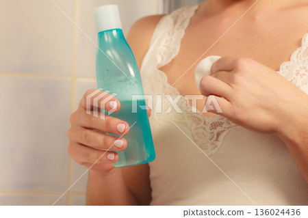 Woman cleaning neckline with cotton swab pad 136024436