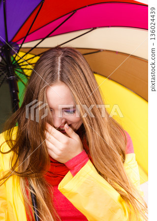 Woman under umbrella sneezing Woman under umbrella sneezing 136024439