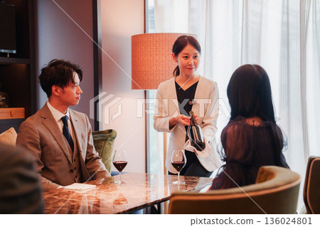 A female staff member recommending wine to a customer A female staff member recommending wine to a customer 136024801