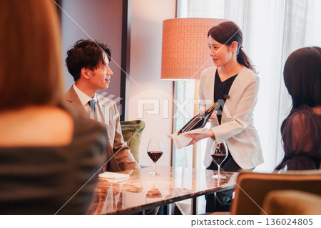 A female staff member recommending wine to a customer A female staff member recommending wine to a customer 136024805