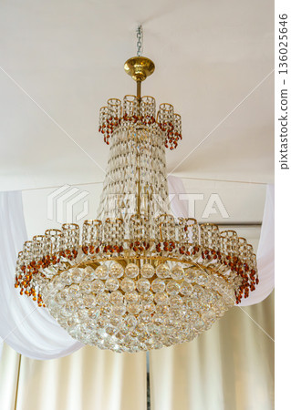 Luxury crystal chandelier hanging in elegant classic interior with white curtains Luxury crystal chandelier hanging in elegant classic interior with white curtains 136025646