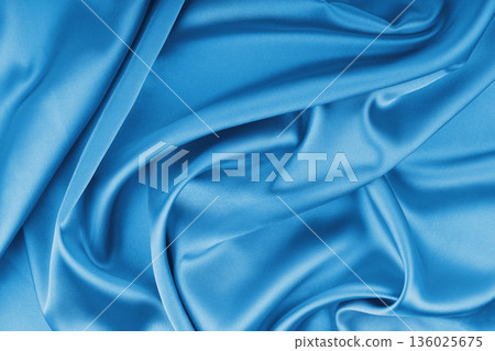 Crumpled, wrinkled cyan colored glossy silk satin texture. Shiny fabric cloth with wave folds 136025675