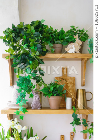 Easter decor with green plants, bunny figurine and spring home interior details on wooden shelf Easter decor with green plants, bunny figurine and spring home interior details on wooden shelf 136025713