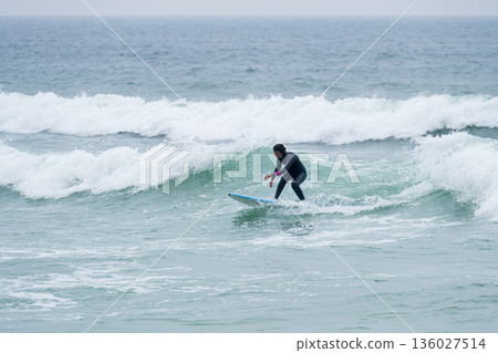 Surfer girl riding a wave 136027514