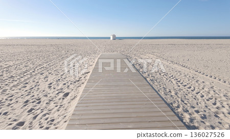 A wide wooden walkway stretches across a vast, pristine beach A wide wooden walkway stretches across a vast, pristine beach 136027526