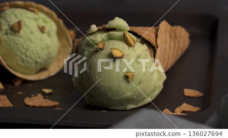 Pistachio Ice Cream in Waffle Cones with Crushed Nuts on Dark Background Pistachio Ice Cream in Waffle Cones with Crushed Nuts on Dark Background 136027694