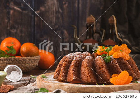 Glazed Tangerine Bundt Cake on Wooden Board with Citrus and Mint 136027699