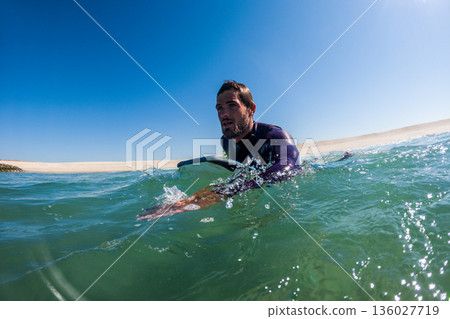 Bodyboarder rowing over the water Bodyboarder rowing over the water 136027719
