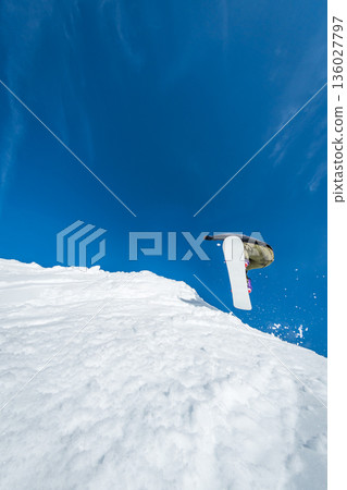Snowboarder jumping against blue sky Snowboarder jumping against blue sky 136027797