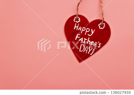 Wooden red heart with white inscription happy Father's day on twine and pink background 136027930