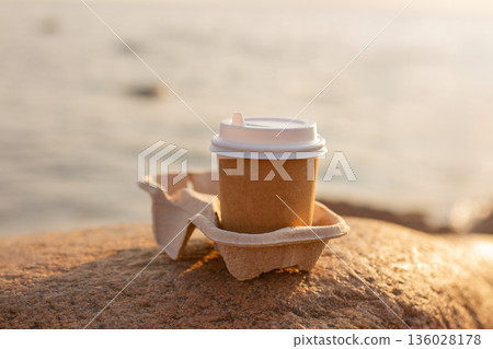 One brown cup of drink in stand for two on stone on sea beach One brown cup of drink in stand for two on stone on sea beach 136028178