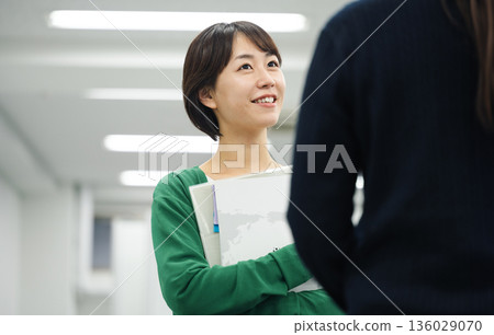 一位年輕的職業婦女正在和同事聊天 136029070