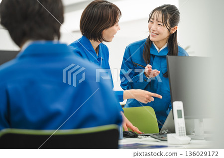 Young woman in work clothes discussing with her colleague in the office Young woman in work clothes discussing with her colleague in the office 136029172