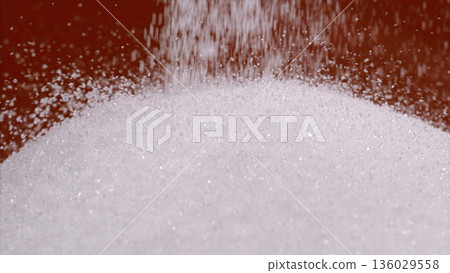 Sugar pours from above into a round bowl on a kitchen counter during a cooking session Sugar pours from above into a round bowl on a kitchen counter during a cooking session 136029558