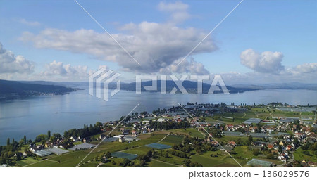 Sky view of a lake area with homes and fields near the water in Switzerland during a sunny day in summer Sky view of a lake area with homes and fields near the water in Switzerland during a sunny day in summer 136029576