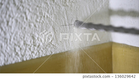 Drilling a hole in a wall for installation of fittings or fixtures in a home setting 136029642