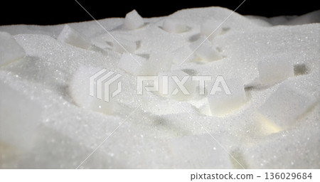 Many sugar cubes scattered on white granulated sugar background creating a simple yet detailed composition for artistic purposes 136029684