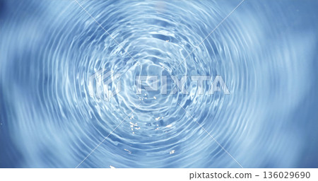 Ripples form on water surface after stone is thrown into lake in bright sunlight creating beautiful patterns 136029690