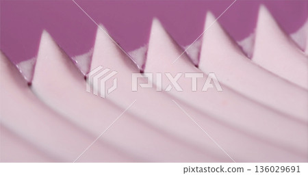 Close view of a wavy pink surface with sharp peaks created by a textured object in a light setting Close view of a wavy pink surface with sharp peaks created by a textured object in a light setting 136029691