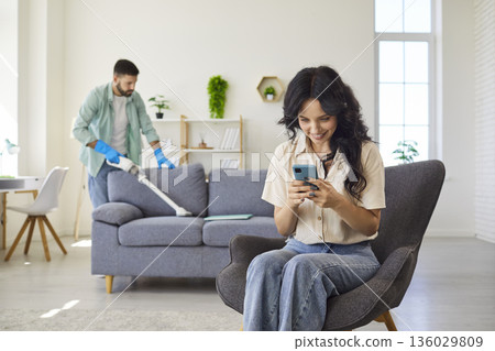Happy woman using smartphone, looking in secret at screen to read hidden messages Happy woman using smartphone, looking in secret at screen to read hidden messages 136029809