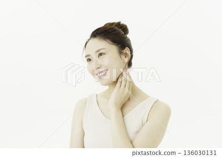 一位年輕的日本女子穿著背心，在白色背景前，撫摸著自己的脖子。 136030131