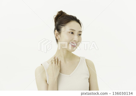 一位年輕的日本女子穿著背心，在白色背景前，撫摸著自己的脖子。 136030134