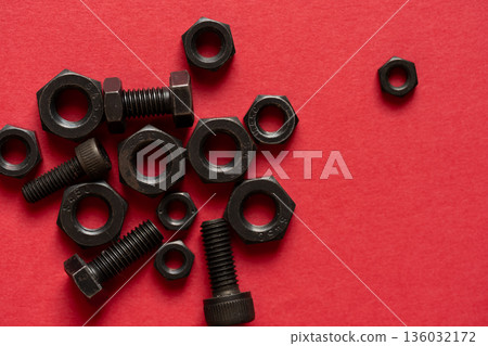 Hexagonal bolt and nut on a red background Hexagonal bolt and nut on a red background 136032172