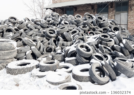 Old tires are stacked in a recycling yard located in a cold area showing the process of reusing rubber and reducing landfill waste. High quality photo 136032374