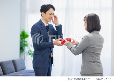 辦公室裡,一位女士送給一位男士一份禮物。 辦公室裡,一位女士送給一位男士一份禮物。 136032382