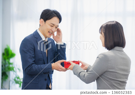 辦公室裡，一位女士送給一位男士一份禮物。 136032383