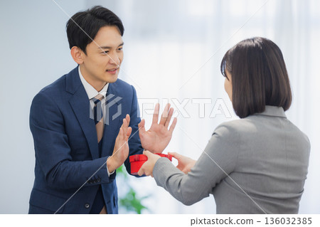 A woman giving a gift to a man in the office 136032385