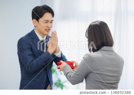 A woman giving a gift to a man in the office 136032386