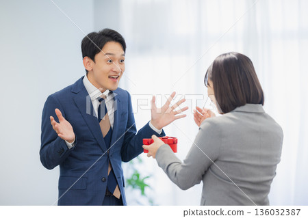 辦公室裡，一位女士送給一位男士一份禮物。 136032387
