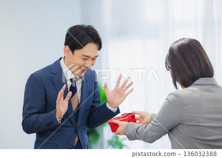 辦公室裡,一位女士送給一位男士一份禮物。 辦公室裡,一位女士送給一位男士一份禮物。 136032388