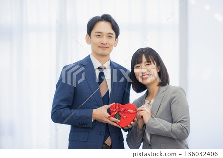 A woman giving a gift to a man in the office 136032406