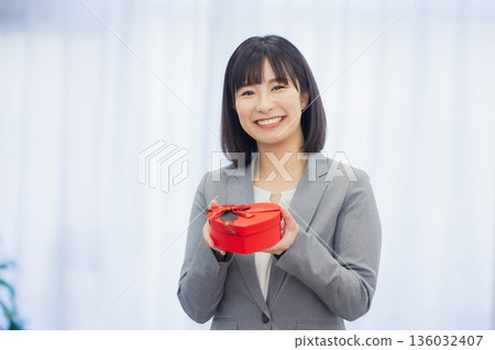 辦公室裡，一位女士送給一位男士一份禮物。 136032407