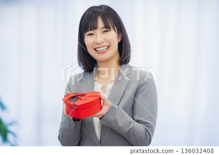 A woman giving a gift to a man in the office A woman giving a gift to a man in the office 136032408