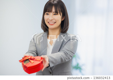 A woman giving a gift to a man in the office A woman giving a gift to a man in the office 136032413