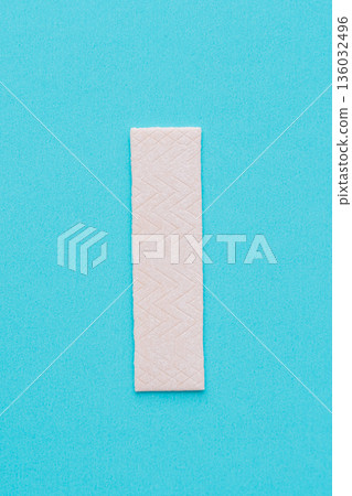 Single chewing gum stick on turquoise background, minimal concept Single chewing gum stick on turquoise background, minimal concept 136032496