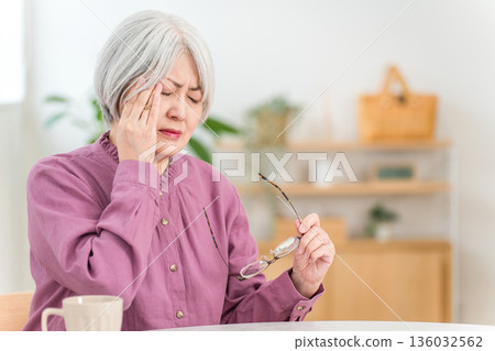 一位銀髮老婦,飽受偏頭痛、頭痛和眼睛疲勞的折磨。 一位銀髮老婦,飽受偏頭痛、頭痛和眼睛疲勞的折磨。 136032562