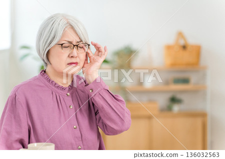 一位銀髮老婦,飽受偏頭痛、頭痛和眼睛疲勞的折磨。 一位銀髮老婦,飽受偏頭痛、頭痛和眼睛疲勞的折磨。 136032563