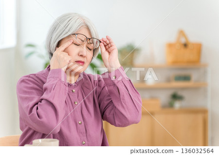 一位銀髮老婦，飽受偏頭痛、頭痛和眼睛疲勞的折磨。 136032564
