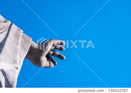 Buddha statue's hand outstretched against the blue sky. Spiritual background material with ample copy space Buddha statue's hand outstretched against the blue sky. Spiritual background material with ample copy space 136032567